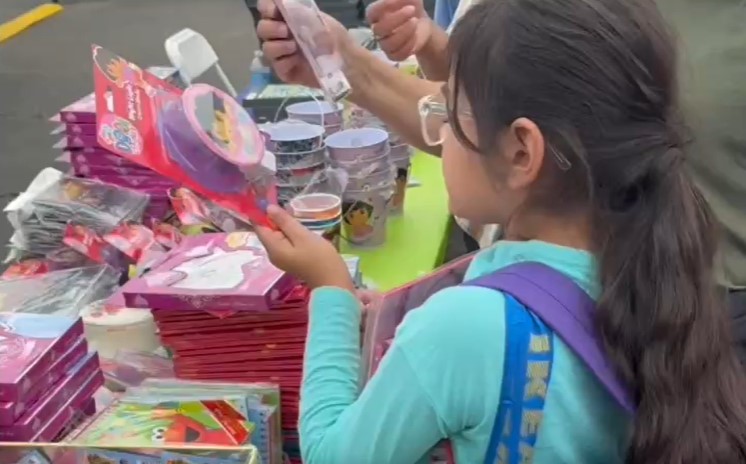 San Bernardino parole agents helped families at a recent event put on by the Children's Fund. A child is shown selecting from a table of school supplies and toys.